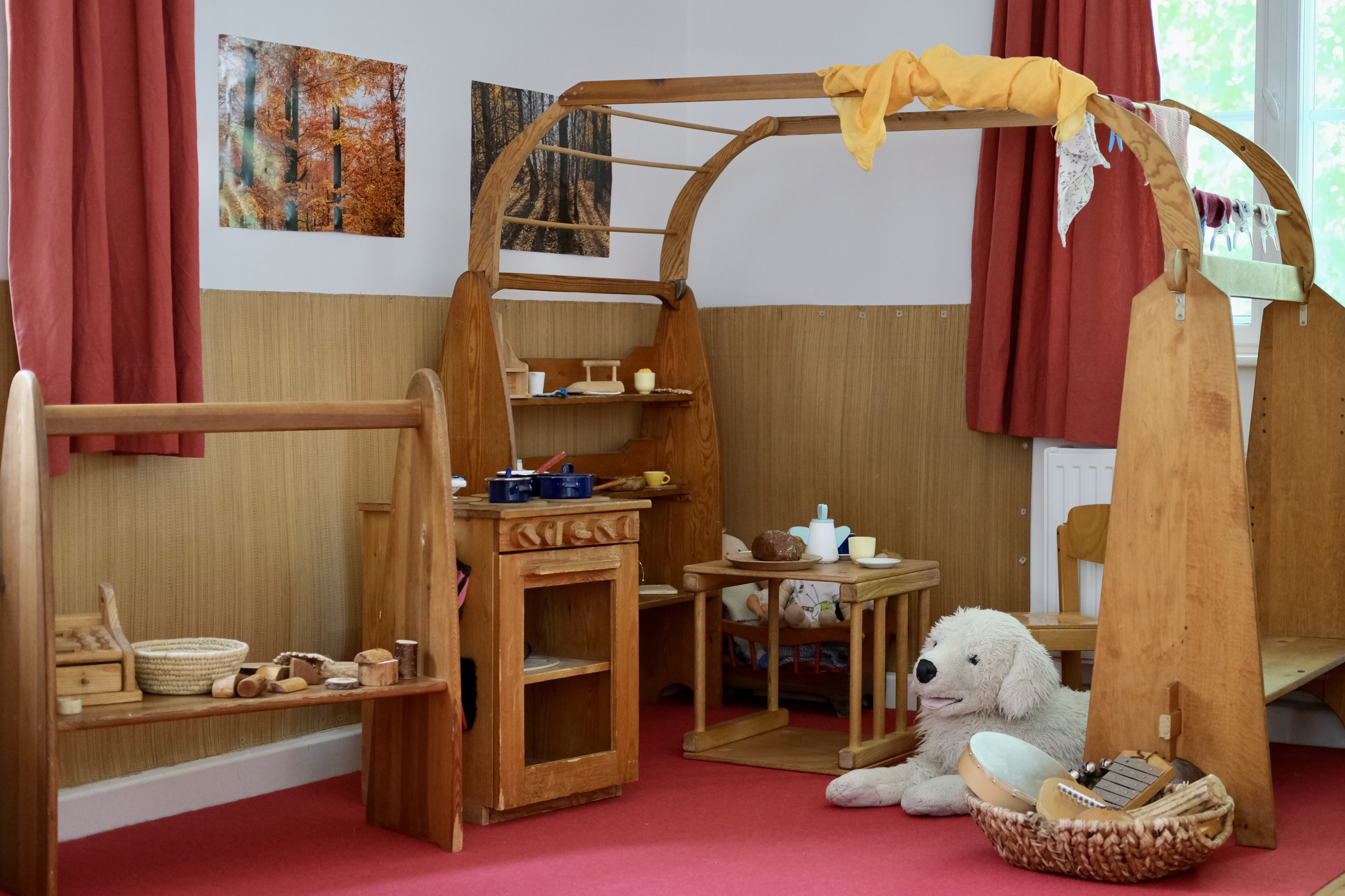 Helles Spielzimmer mit Maltisch, Farben und Kinderzeichnungen an der Wand